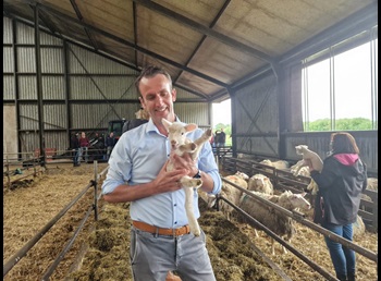 Dirk Bruins houdt een lammetje vast tijdens een rondleiding door een biologische schapenhouderij
